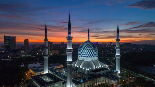 Modern buildings in city against sky during sunset