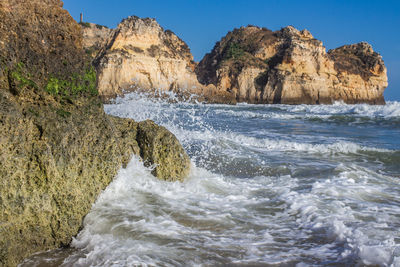 Scenic view of rocks in sea against sky