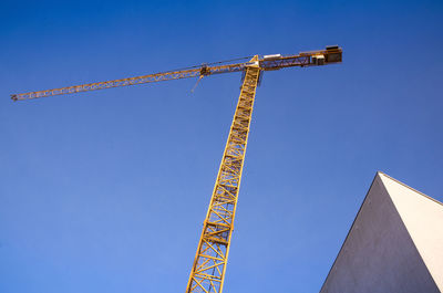 Low angle view of crane against clear blue sky