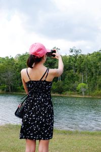 Full length of woman standing by lake against sky