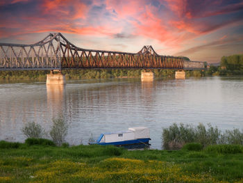 Bridge over river against sky during sunset