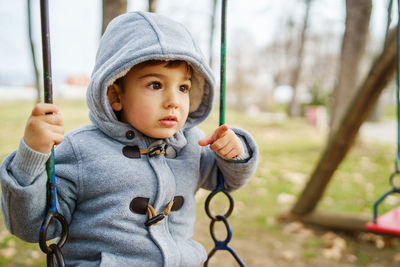 Cute boy sitting on swing sitting at park