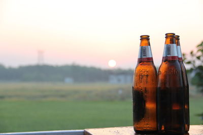 Close-up of beer bottle on table against sky during sunset