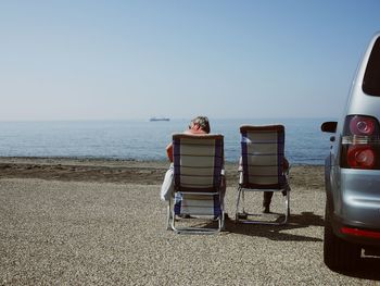 Lounge chairs on beach against clear sky