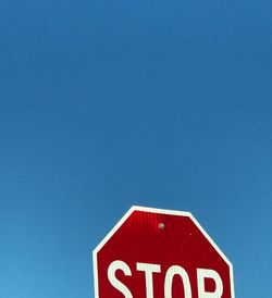 Close-up of road sign against clear blue sky