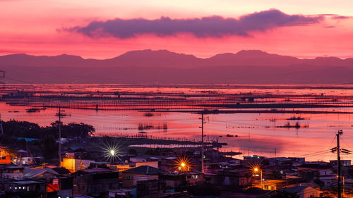 Illuminated cityscape against sky during sunrise