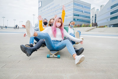 Cheerful friends wearing sitting on skateboard