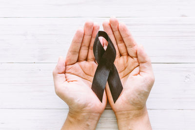Cropped hands holding black ribbon on table