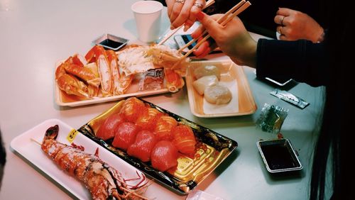 Cropped image of women having sushi at table in restaurant