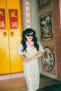 Portrait of young woman standing against wall