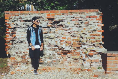 Full length of man leaning on wall during sunny day