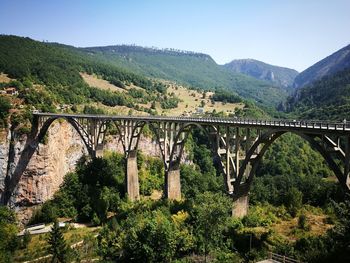 Bridge over river amidst mountains against clear sky