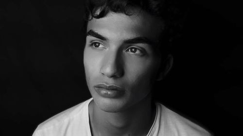 Close-up portrait of young man against black background