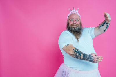 Portrait of man dancing against pink background