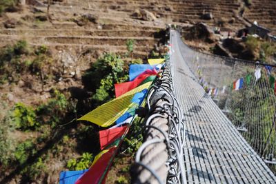 Multi colored flags hanging on railing against trees