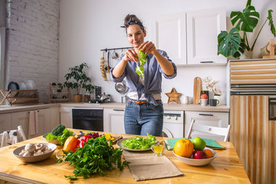 Young and beautiful housewife woman cooking in a white kitchen