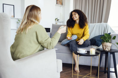 Mother and daughter sitting on sofa at home