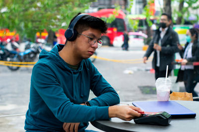 Side view of man using digital tablet in city