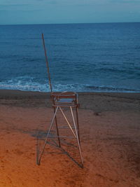 Lifeguard chair on beach against sky