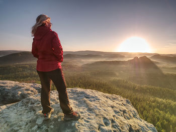 Blond hair girl tourist enjoy achievement of rocky summit with fantastic view into morning landscape