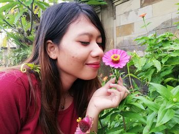 Beautiful young woman holding pink flower