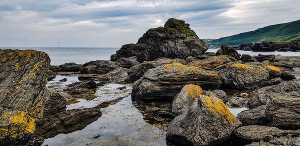 Rock formation on beach against sky