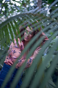 Thoughtful mature woman standing by plants at park