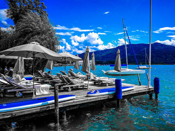 Boats moored at beach against blue sky