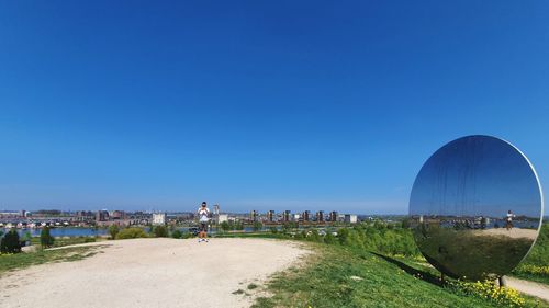 People on beach against clear blue sky