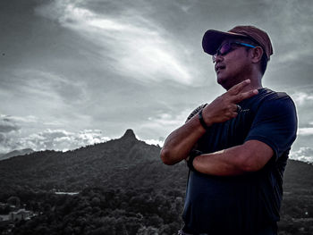 Side view of young man looking away against mountain