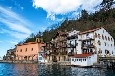 Buildings by river against sky