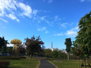 Street amidst trees in park against blue sky