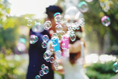 Close-up of bubbles with couple kissing in background