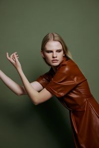 Portrait of young woman standing against wall