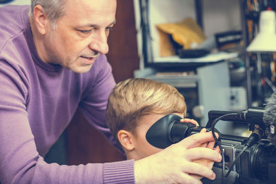 Grandfather teaching boy to use video camera