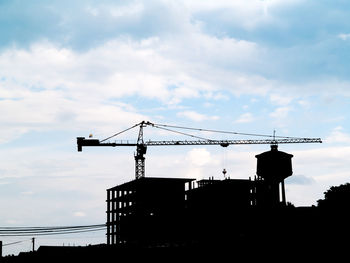 Low angle view of silhouette crane against sky