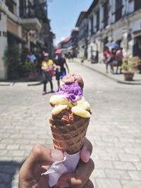 Person holding ice cream cone on street