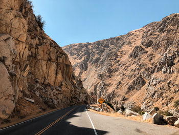 Road leading towards mountains against clear sky