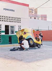 Boy sitting on motorcycle against sky in city