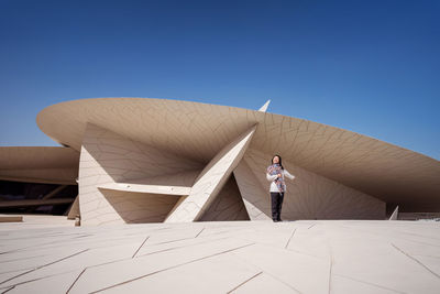 Rear view of man standing against clear blue sky