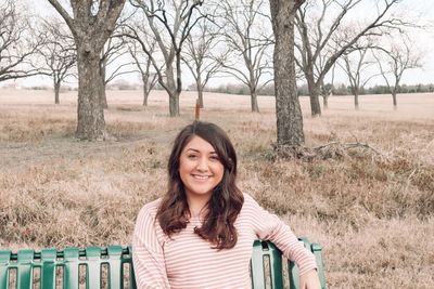 Portrait of smiling young woman sitting on a bench.