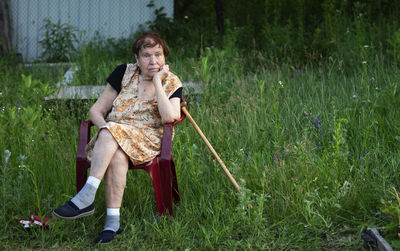 Full length of senior woman sitting on chair in back yard