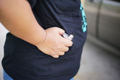 Midsection of man holding electronic cigarette