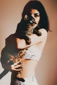 Portrait of woman with cat against gray background