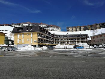 Road by buildings in city against sky