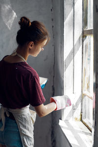 Side view of young woman painting wall