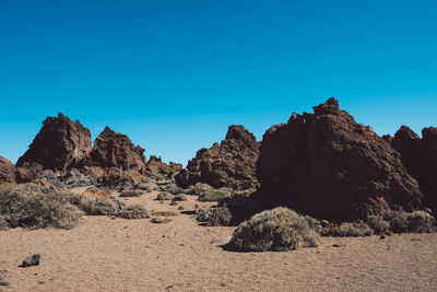 Rock formations on landscape against clear blue sky