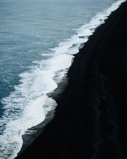 High-angle view of sea waves in a black sand beach