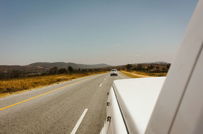 Road leading towards mountains against clear sky in tanzania 