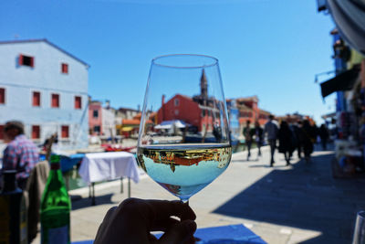 Close-up of hand holding drink against sky